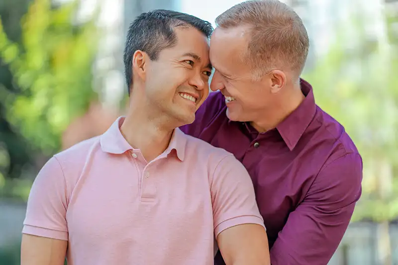 Gay couple smiling together while learning about surrogacy for LGBTQ+ intended parents with Global Surrogacy Services