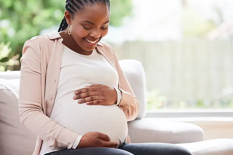 Pregnant surrogate sitting comfortably while intended parents plan for surrogacy cost factors and pregnancy-related expenses