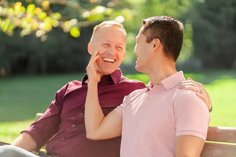 Same-sex male couple smiling together while exploring surrogacy options for intended parents
