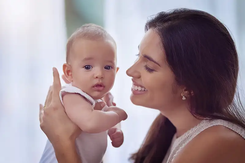 Mother smiling at baby in a bright home setting representing donor egg family-building support through Global Surrogacy Services.