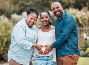 Woman and man making a heart on the pregnant belly of a woman who is a surrogate