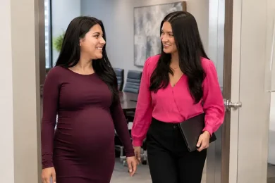Pregnant surrogate walking with a Global Surrogacy Services team member while learning about surrogate compensation benefits and support.